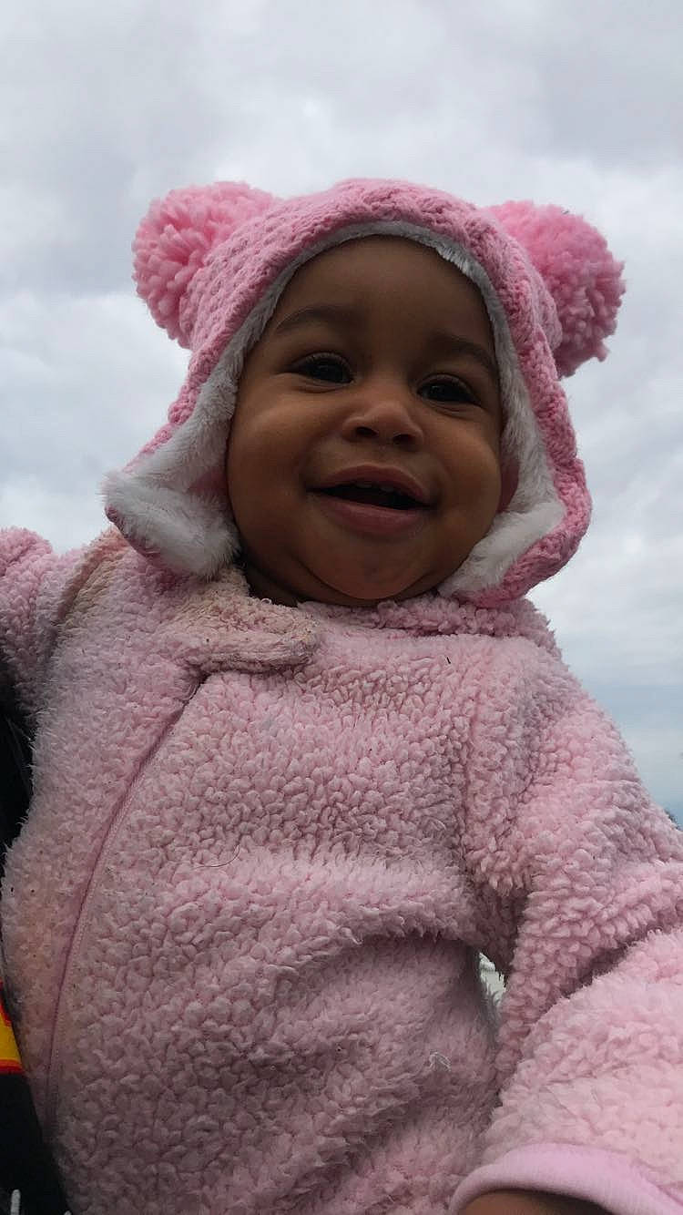 Spirit is registered to the contest to win money with this photo: baby, cheek, clothing, eye, face, happy, head, headwear, iris, joy, lip, mouth, nose, organ, outerwear, parka, person, pink, skin, sky