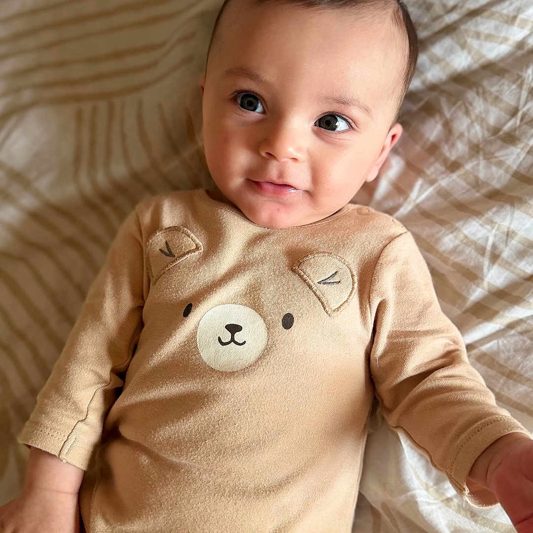 Ousaid a rejoint le concours — aidez-le/la à gagner de superbes lots ! baby, bear_design, bed, blanket, child, clothing, comfortable, cute, eyes, face, hand, indoors, infant, lying_down, onesie, portrait, skin, smiling, soft, young