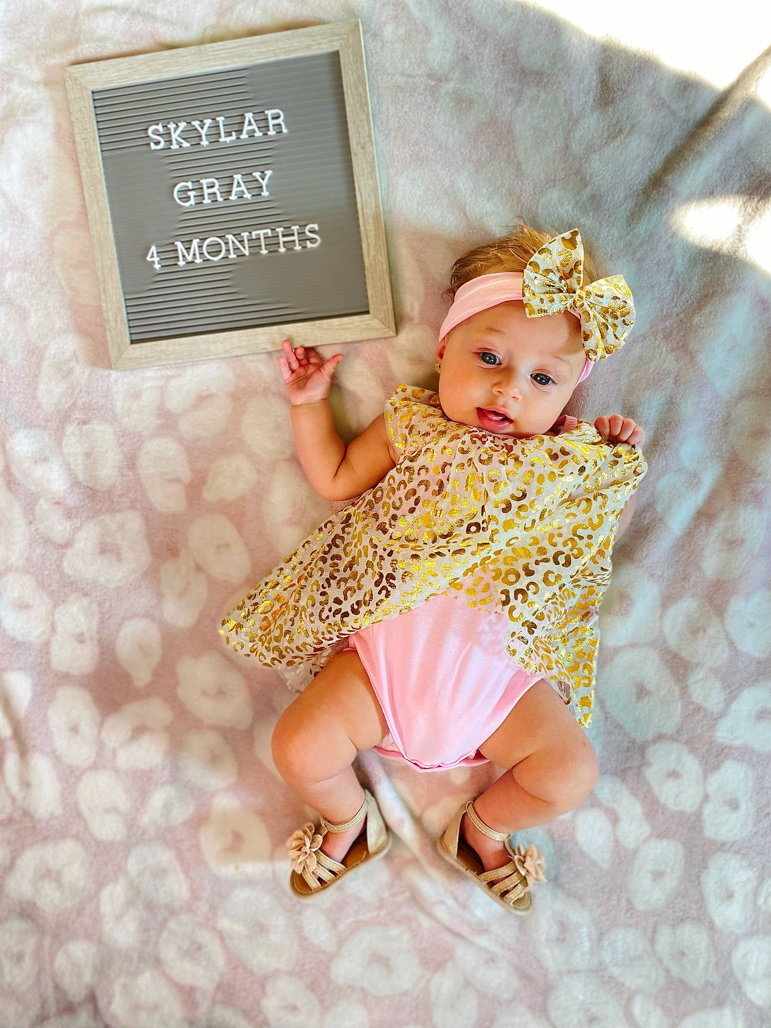 Skylar is registered to the contest to win money with this photo: baby, baby_toddler_clothing, clothing, day_dress, dress, fawn, finger, font, hand, happy, headwear, jewellery, one_piece_garment, pattern, person, pink, product, sandal, skin, sleeve