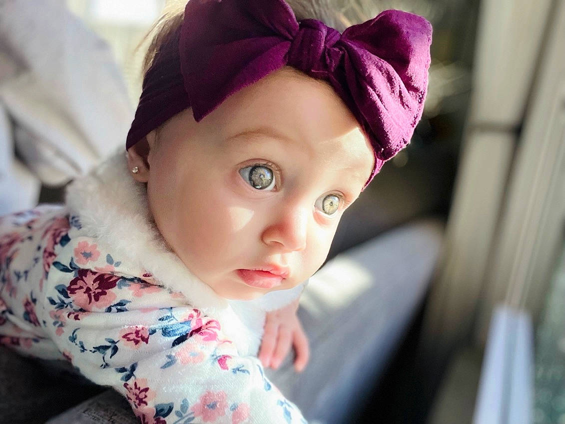 Skylar is registered to the contest to win money with this photo: cap, cheek, child, chin, close_up, doll, eyelash, fashion_accessory, happy, hat, headpiece, headwear, iris, lip, magenta, nose, person, pink, skin, surprise