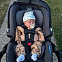 baby, infant, car_seat, stroller, pacifier, hat, sleeping, outdoor, pathway, grass, clothing, socks, child, seatbelt, newborn, toddler, cute, bundle, babywear, carrying