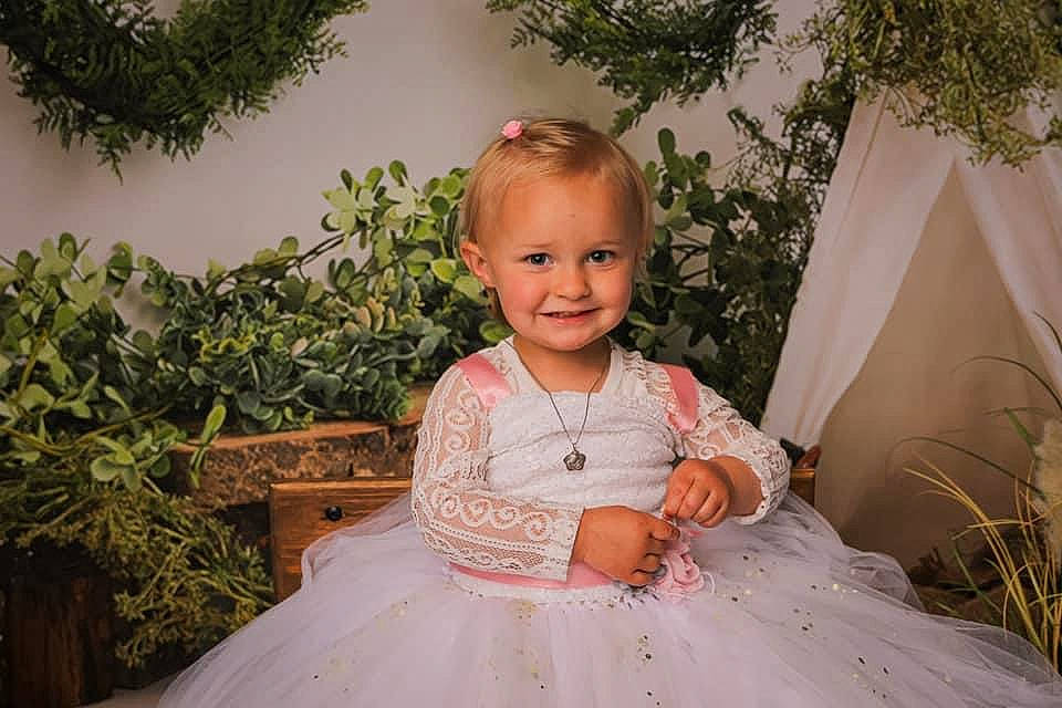 Lucie a rejoint le concours — aidez-le/la à gagner de superbes lots ! baby_toddler_clothing, blond, bridal_clothing, child, dress, event, eye, flash_photography, formal_wear, gown, grass, happy, iris, joy, person, plant, sitting, skin, smile, toddler