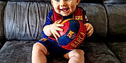 Mael a rejoint le concours — aidez-le/la à gagner de superbes lots ! baby, child, smile, blue_eyes, football, soccer_ball, barcelona, sportswear, couch, indoor, happy, person, sitting, cute, team_spirit, plush, footwear, shorts, jersey, hands