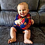 baby, child, smile, blue_eyes, football, soccer_ball, barcelona, sportswear, couch, indoor, happy, person, sitting, cute, team_spirit, plush, footwear, shorts, jersey, hands