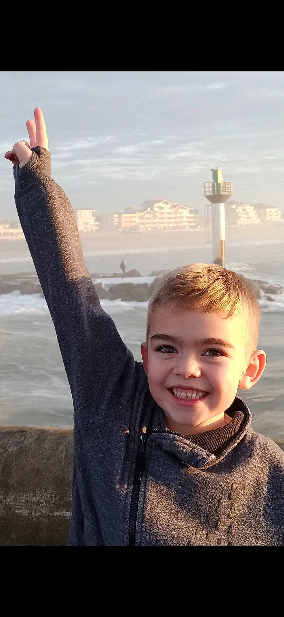 Kélio a rejoint le concours — aidez-le/la à gagner de superbes lots ! beach, cloud, flash_photography, fun, gesture, happy, horizon, human_leg, joy, morning, people, people_in_nature, person, sand, sky, smile, summer, thumb, toddler, travel