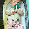 baby, pacifier, baby_seat, pink_shorts, white_shirt, infant, clothing, cute, child, face, hand, comfort, resting, indoor, baby_accessory, clip, expression, looking_up, soft_fabric, cushion