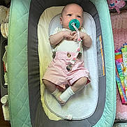 Raelynn is registered to the contest to win money with this photo: baby, pacifier, infant, pink_shorts, baby_lounger, blanket, toy, cushion, white_socks, clothing, lying_down, indoor, child, person, cute, small, comfortable, looking_up, home, nursery