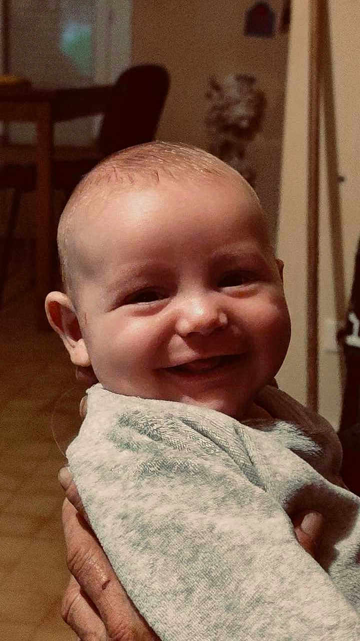 Nolyam a rejoint le concours — aidez-le/la à gagner de superbes lots ! baby, smile, face, hand, blanket, indoor, furniture, person, child, happy, cozy, portrait, head, clothing, skin, adult_hand, warm_light, background, home, closeup