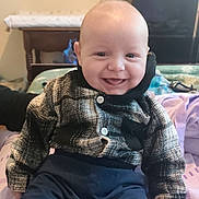 Nolyam participe au concours pour gagner de l'argent avec cette photo : baby, smile, plaid_jacket, navy_pants, child, indoor, bed, happy, portrait, person, clothing, furniture, table, home, cute, infant, sitting, face, cozy, young