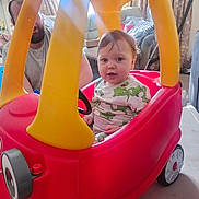 Malakai is registered to the contest to win money with this photo: car, casual_clothing, child, curtains, cute, family, fun, furniture, home, indoor, light, living_room, man, person, plastic, playtime, smiling, sunlight, toddler, toy_car