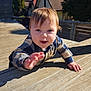 Malakai joined the competition — help win amazing prizes! baby, child, crawling, wooden_deck, outdoor, daylight, smiling, person, hand, face, plaid_shirt, trees, house, roof, blue_sky, sunlight, wood, happy, young_child, nature