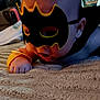 baby, child, mask, costume, superhero, black_mask, yellow_trim, wristband, blanket, crawling, indoor, cute, infant, portrait, face, hand, closeup, playful, young, person