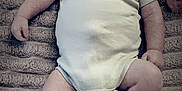 Otis joined the competition — help win amazing prizes! baby, infant, smiling, onesie, text_on_clothing, shoes, socks, blanket, lying_down, happy, child, face, head, footwear, white_shoes, black_stripes, cute, indoors, portrait, person