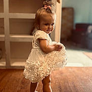 Oaklynn joined the competition — help win amazing prizes! toddler, child, white_dress, barefoot, pink_bow, wooden_floor, indoor, playful, smiling, baby, person, furniture, home, portrait, cute, young_child, flooring, dress, hair_accessory, standing