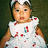 Sofia is registered to the contest to win money with this photo: toddler, child, dress, headband, cherry_pattern, white_dress, sitting, couch, green_couch, indoor, portrait, cute, baby, fashion, clothing, person, face, expression, young_child, headwear