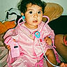 Sofia joined the competition — help win amazing prizes! toddler, child, toy, pink_clothing, doctor_costume, stethoscope, pulse_monitor, bed, indoor, play, curious, person, young_child, imaginative_play, casual, home, seated, black_hair, medical_toy, cozy