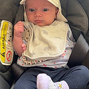 Elisabeth participe au concours pour gagner de l'argent avec cette photo : accessory, baby, bib, cap, car_seat, child, closeup, clothing, cute, expression, face, hand, indoors, infant, person, safety, seatbelt, sitting, sock, toy