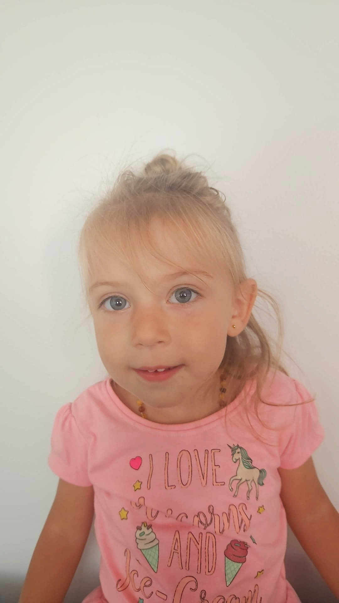 Naomi a rejoint le concours — aidez-le/la à gagner de superbes lots ! child, girl, blonde_hair, blue_eyes, pink_shirt, unicorn, ice_cream, smile, portrait, casual_clothing, cute, young, face, earrings, necklace, indoor, white_background, happy, toddler, childhood