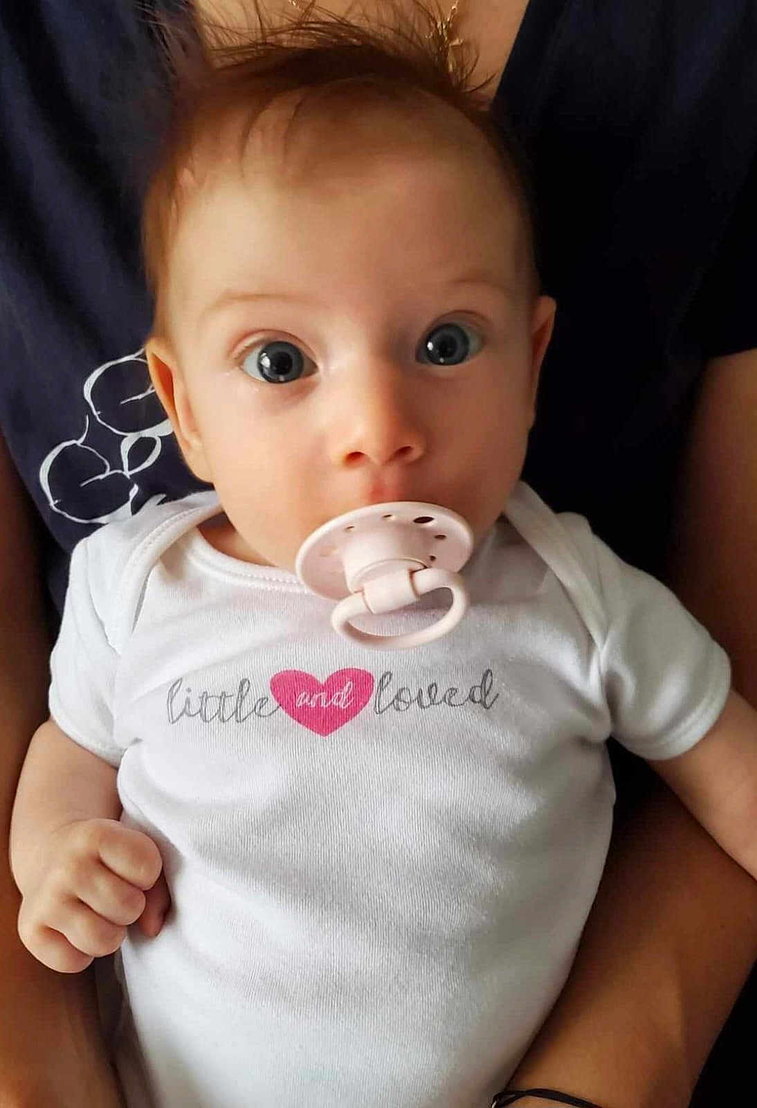 Debora participe au concours pour gagner de l'argent avec cette photo : baby, infant, pacifier, onesie, white_clothing, child, person, holding, hands, cute, wide_eyes, hair, face, portrait, close_up, love, toddler, skin, baby_girl, candid