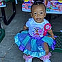 Kennedi joined the competition — help win amazing prizes! toddler, birthday, girl, tutu, sneakers, ribbon, picnic_table, hairstyle, pigtails, party, decorations, animated_characters, smiling, outdoor, clothing, celebration, child, person, seat, concrete_floor