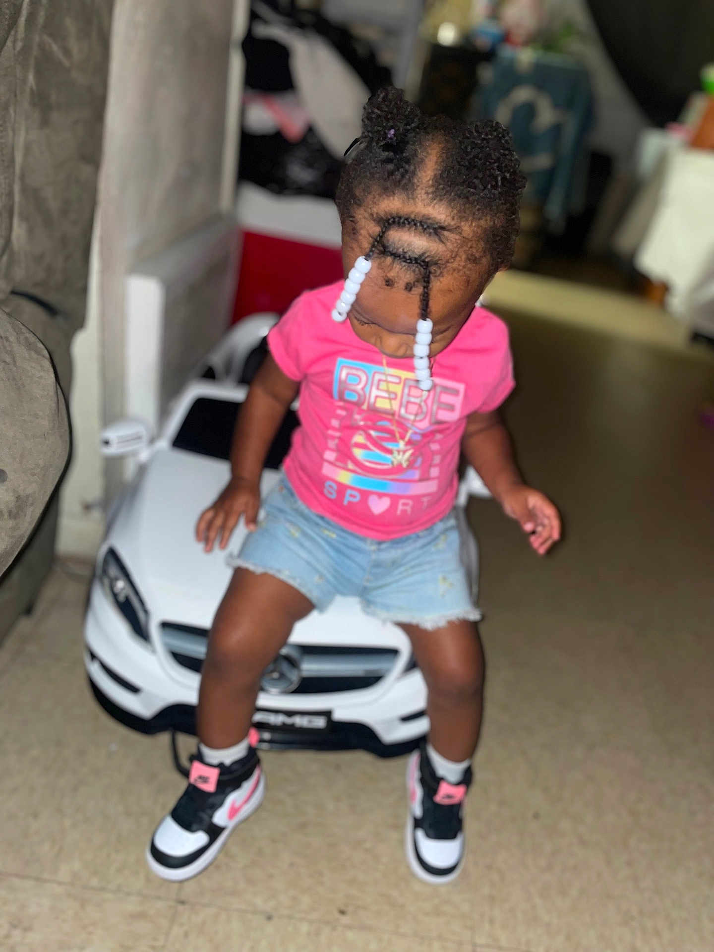 Kennedi joined the competition — help win amazing prizes! child, toddler, toy_car, indoor, braided_hair, beads, pink_shirt, denim_shorts, sneakers, floor, car, playing, cute, young_child, person, casual_clothing, fun, small_vehicle, looking_down, home