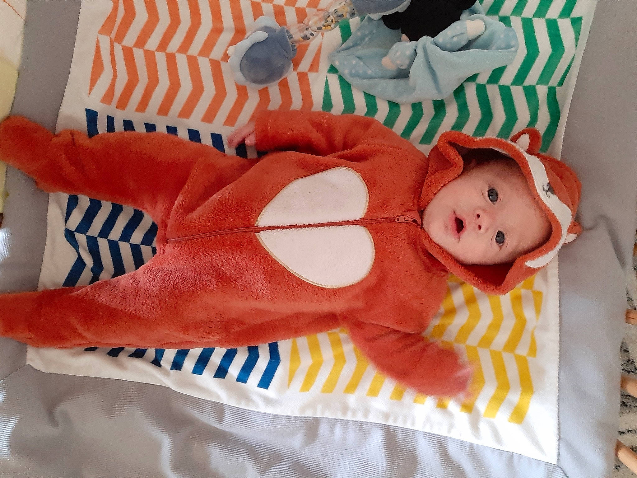 Hayden a rejoint le concours — aidez-le/la à gagner de superbes lots ! baby, baby_products, baby_toddler_clothing, baby_toys, bed_sheet, bedding, child, comfort, happy, headwear, linens, orange, pattern, person, pink, product, room, smile, stuffed_toy, textile