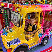 Théo participe au concours pour gagner de l'argent avec cette photo : amusement_park, boy, bright_colors, carnival, cartoon_characters, child, colorful, entertainment, fun, happy, indoor, lights, minions, playful, ride, seat, toy_car, vehicle, yellow_overalls, young_child