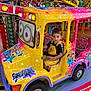 amusement_park, boy, bright_colors, carnival, cartoon_characters, child, colorful, entertainment, fun, happy, indoor, lights, minions, playful, ride, seat, toy_car, vehicle, yellow_overalls, young_child