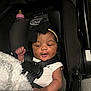 Normani is registered to the contest to win money with this photo: baby, infant, car_seat, black_bow, headband, white_onesie, blanket, bottle, safety_harness, cute, smiling, indoors, child, newborn, person, seat, soft_texture, black_fabric, closeup, resting