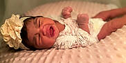 Normani is registered to the contest to win money with this photo: baby, newborn, infant, lace, headband, flower, blanket, pink, soft, texture, clothing, portrait, crying, fist, sleepwear, cute, child, lying_down, indoors, closeup