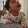 baby, child, pajamas, blanket, face, hand, bedroom, indoor, soft_lighting, toy_horse, curtain, smiling, cute, infant, portrait, cozy, warm, happy, toddler, resting