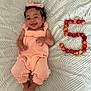 baby, child, smiling, peach_outfit, headband, bow, cherries, number_5, blanket, texture, happy, lying_down, cute, infant, skin, hands, feet, face, fruit, playful
