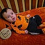 Oliver is registered to the contest to win money with this photo: baby, baby_clothing, bat_pattern, black_pants, child, closeup, cradle, cute, expression, head, indoor, infant, lying_down, orange_blanket, orange_shirt, portrait, pumpkin_pillow, striped_socks, two_months, wooden_bars
