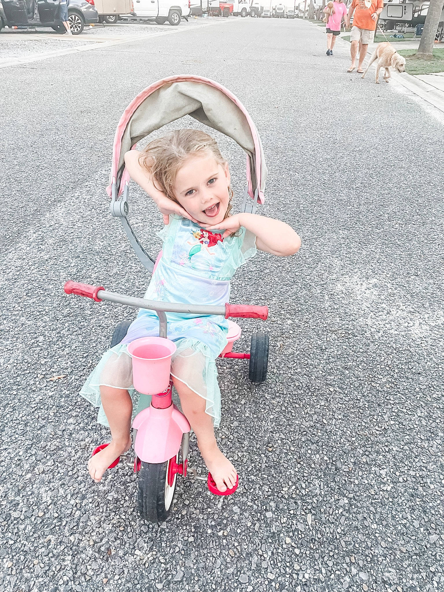 Winnie is registered to the contest to win money with this photo: asphalt, automotive_tire, automotive_wheel_system, city, dress, event, fun, grass, happy, joy, magenta, motor_vehicle, person, pink, plant, road, road_surface, smile, tire, toddler