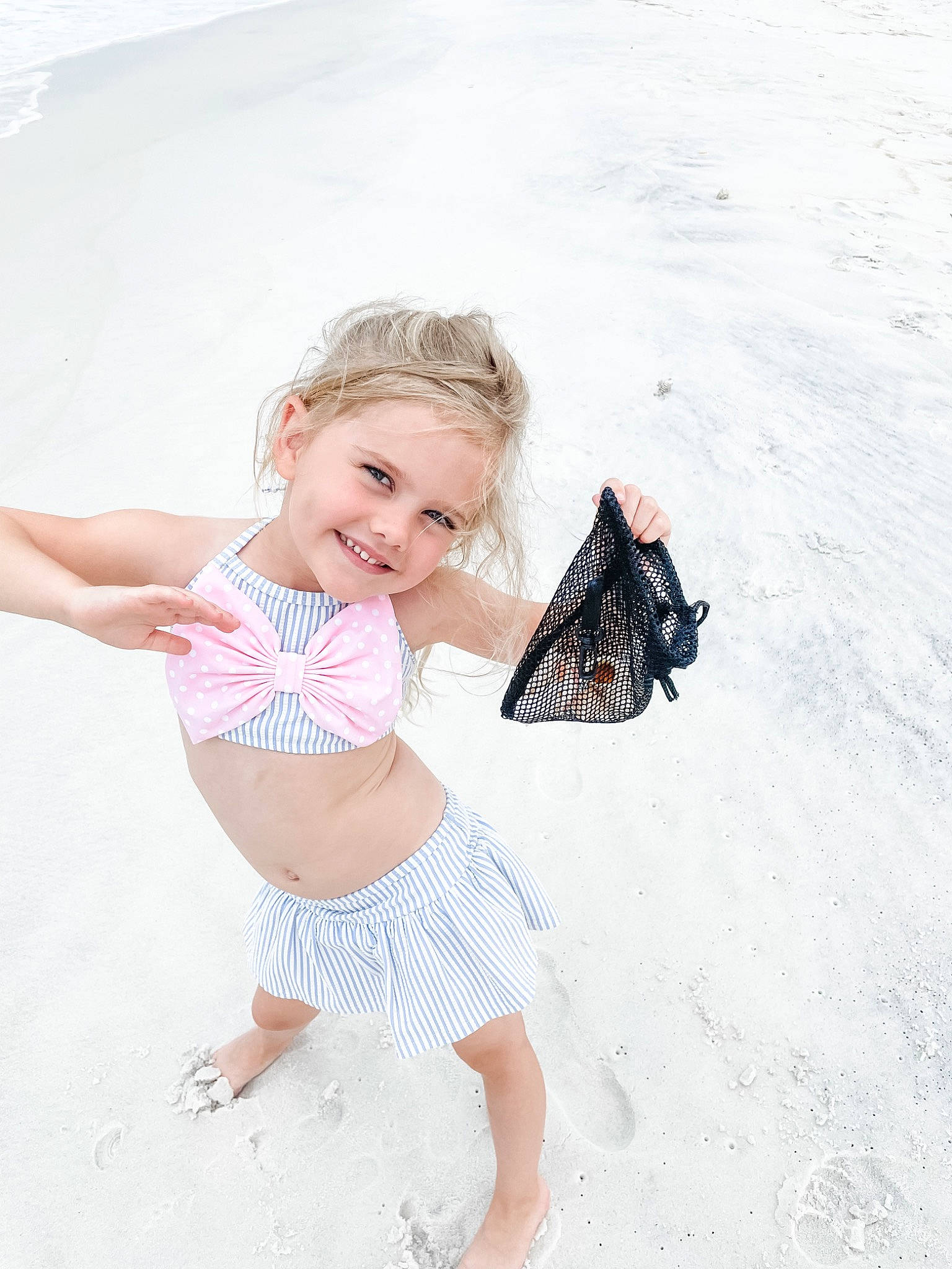 Winnie joined the competition — help win amazing prizes! baby_toddler_clothing, barefoot, blond, child, face, foot, fun, happy, human_leg, joy, leg, pattern, person, sand, shorts, sitting, sleeve, smile, t_shirt, thigh