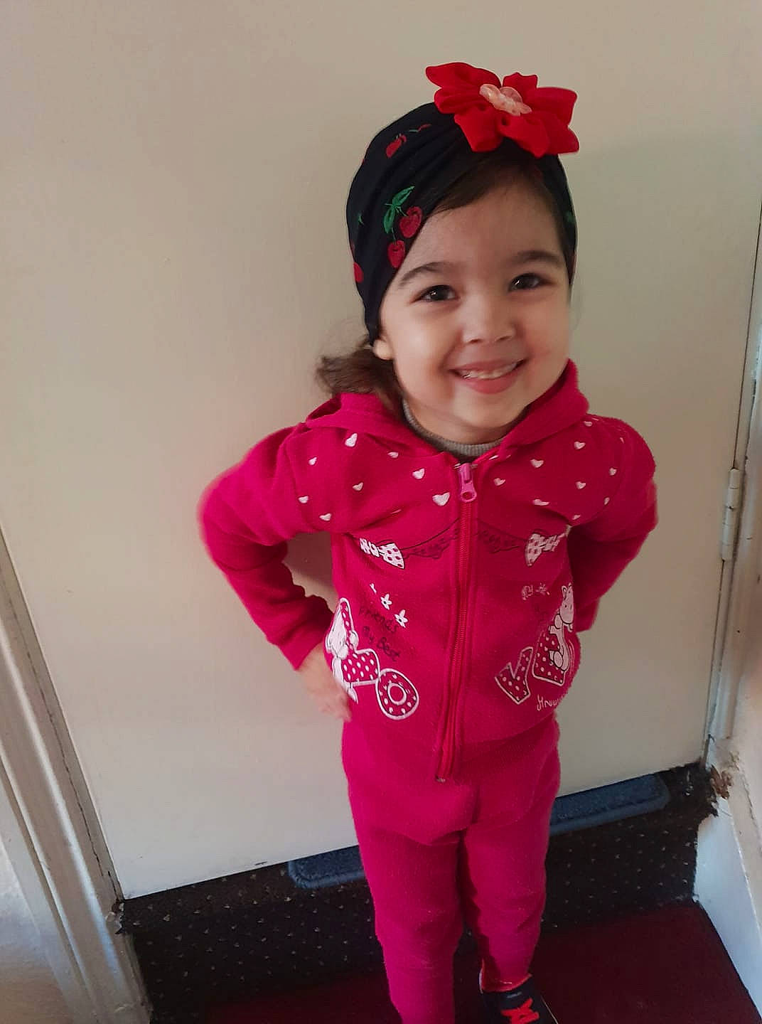 Maya is registered to the contest to win money with this photo: baby_toddler_clothing, child, clothing, costume, hair_accessory, hoodie, joy, outerwear, pajamas, person, pink, red, skin, sleeve, smile, standing, t_shirt, toddler