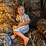 armchair, barefoot, blond_hair, boy, camouflage, casual, child, cozy, device, funny_expression, furniture, indoor, living_room, photography, portrait, sitting, smiling, striped_shirt, tablet, toddler