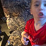 Waylon is registered to the contest to win money with this photo: child, young_child, portrait, indoor, living_room, red_shirt, sitting, face, head, hands, arms, fish_face, expression, couch, chair, phone, floor, furniture, casual, blurry