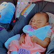 Isla is registered to the contest to win money with this photo: baby, bib, canopy, car_interior, car_seat, child, child_seat, floral_pattern, footwear, hand, indoors, infant, pacifier, peaceful, pink_clothing, portrait, seatbelt, sleeping, transportation, white_socks