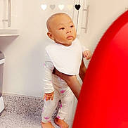 Isla is registered to the contest to win money with this photo: baby, child, toddler, kitchen, countertop, bib, pajamas, floral, barefoot, hands, adult, stove, cabinets, curious, standing, indoor, appliance, person, home, domestic
