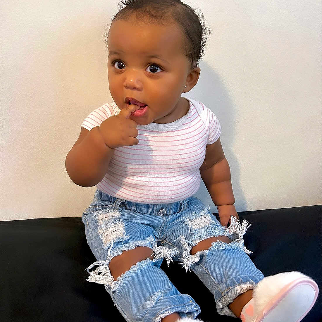 Zendaya is registered to the contest to win money with this photo: baby, biting, bodypart, clothing, eating, face, finger, food, footwear, hand, head, jeans, pants, person, photography, portrait, shoe, shorts, sitting, sneaker