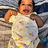 baby, smiling, infant, onesie, clothing, happy, face, arms, lying_down, blanket, striped, pattern, cute, child, skin, person, toddler, portrait, indoors, expression
