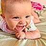 baby, smiling, face, infant, lying_down, hand, cheerful, skin, head, person, cute, expression, indoors, clothing, pink, soft_surface, toy, happy, closeup, child