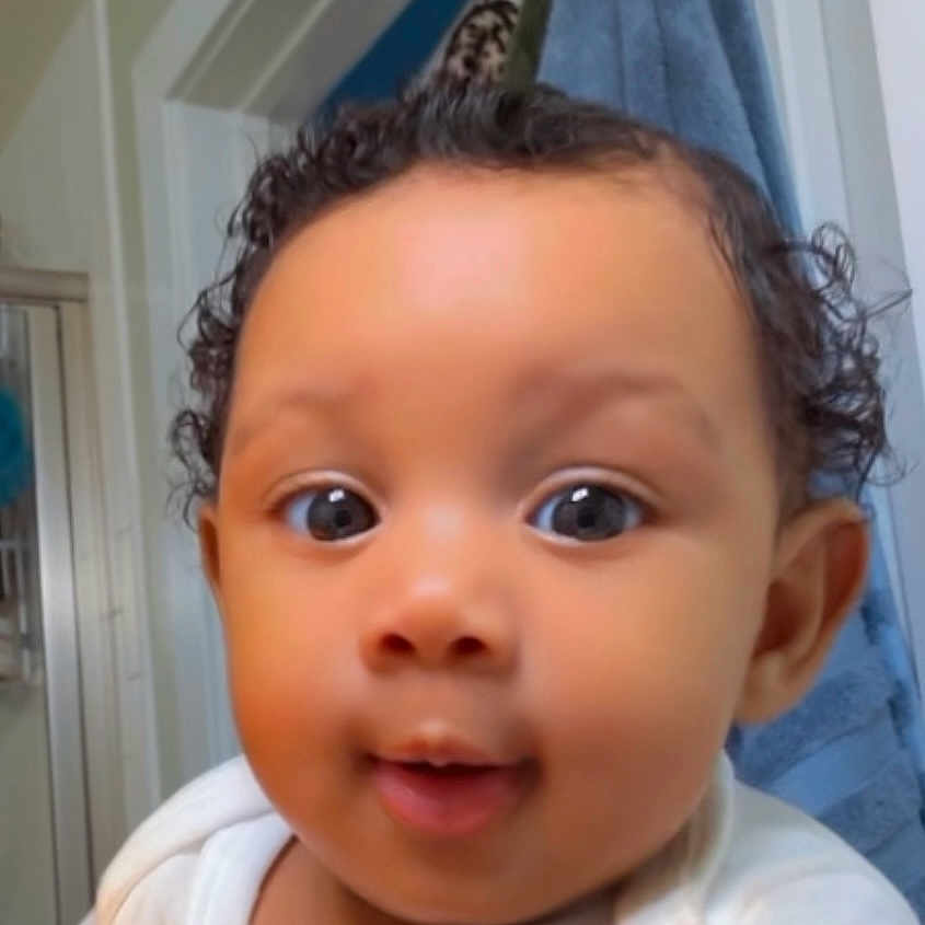 Naylani joined the competition — help win amazing prizes! baby, bathroom, child, close_up, clothing, curiosity, curly_hair, cute, expression, eyes, face, head, indoors, infant, person, portrait, skin, smile, towel, young