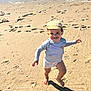 Gaspard a rejoint le concours — aidez-le/la à gagner de superbes lots ! child, toddler, beach, sand, barefoot, hat, running, smiling, water, footprints, sunlight, shadow, shore, playful, summer, clothing, person, outdoor, happy, nature
