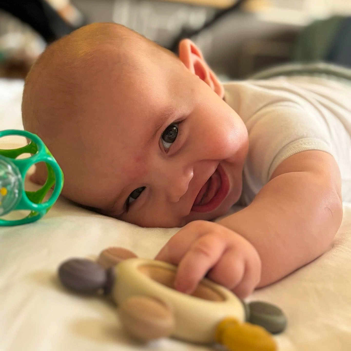 Eliott participe au concours pour gagner de l'argent avec cette photo : baby, cheerful, child, closeup, cute, expression, face, furniture, hand, happy, head, indoor, infant, lying_down, person, playing, skin, smiling, toy, young