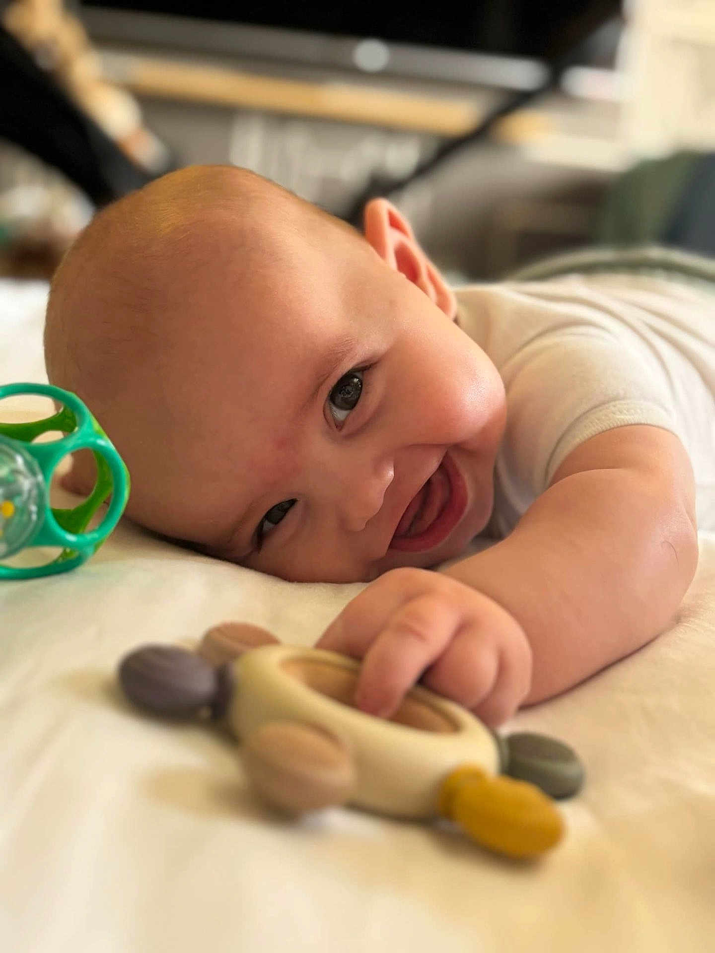 Eliott participe au concours pour gagner de l'argent avec cette photo : baby, smiling, toy, infant, happy, hand, face, lying_down, cute, child, skin, indoor, playing, closeup, expression, cheerful, young, person, head, furniture