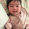 baby, infant, smile, happy, face, onesie, pink, heart_pattern, blanket, floral, cozy, cute, child, portrait, lying_down, soft, warm, newborn, closeup, person