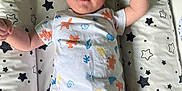 Giuliano participe au concours pour gagner de l'argent avec cette photo : baby, child, infant, lying_down, shirt, shorts, cushion, star_pattern, raised_arm, face, person, indoors, cute, smiling, young_child, clothing, bed, resting, toddler, happy