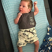 Giuliano a rejoint le concours — aidez-le/la à gagner de superbes lots ! baby, infant, child, clothing, shorts, shirt, mattress, striped, plush_toy, blanket, blue, green, person, lying_down, palm_tree_pattern, raised_fist, cute, indoors, fabric, young